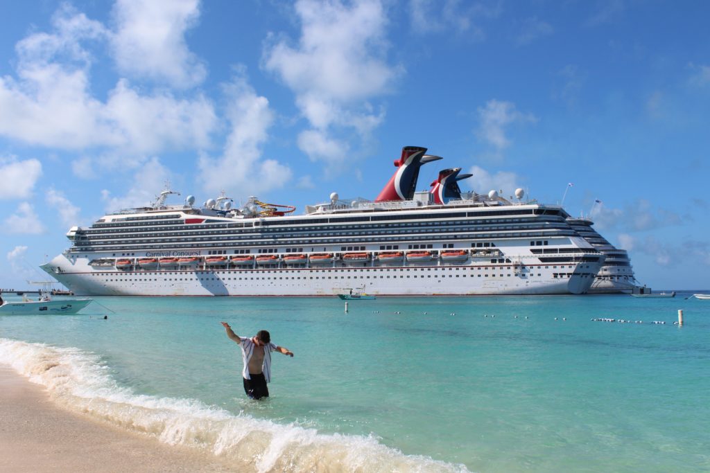 a man standing in the water next to a large cruise ship