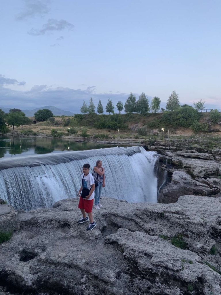 a group of people standing on rocks by a waterfall