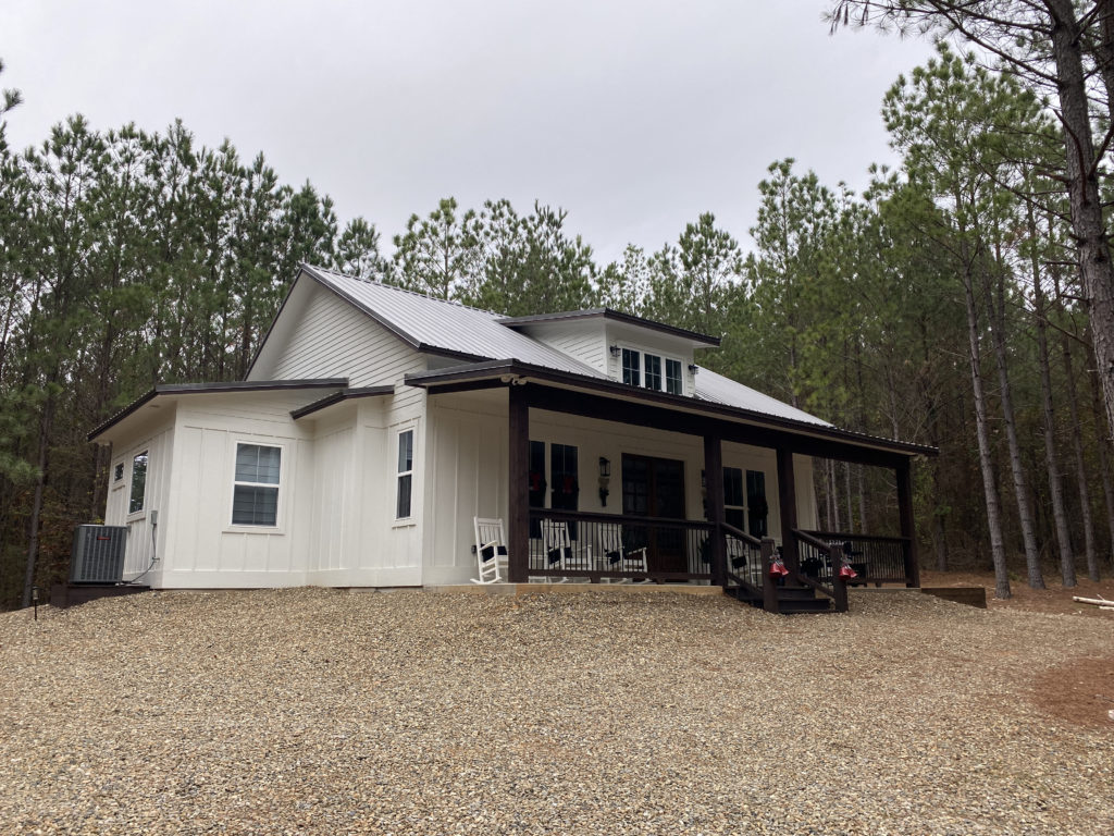 a white house with a gravel driveway and trees