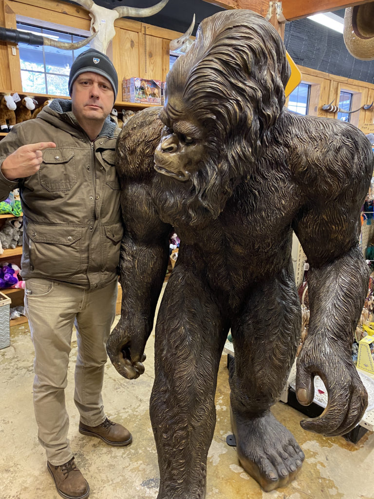 a man standing next to a statue of a gorilla