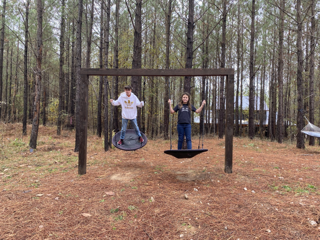 a man and woman on swings in a forest