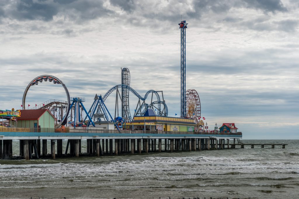 a pier with a roller coaster and a building on it