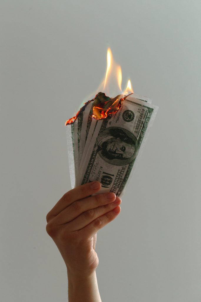 a hand holding money on fire