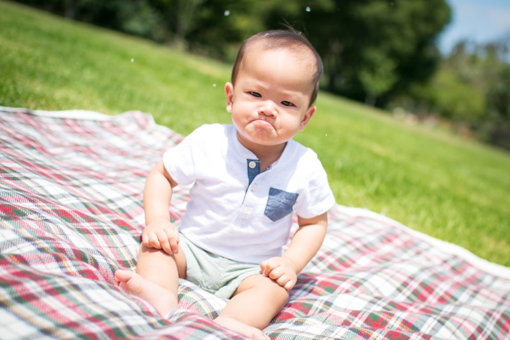 a baby sitting on a blanket in the grass