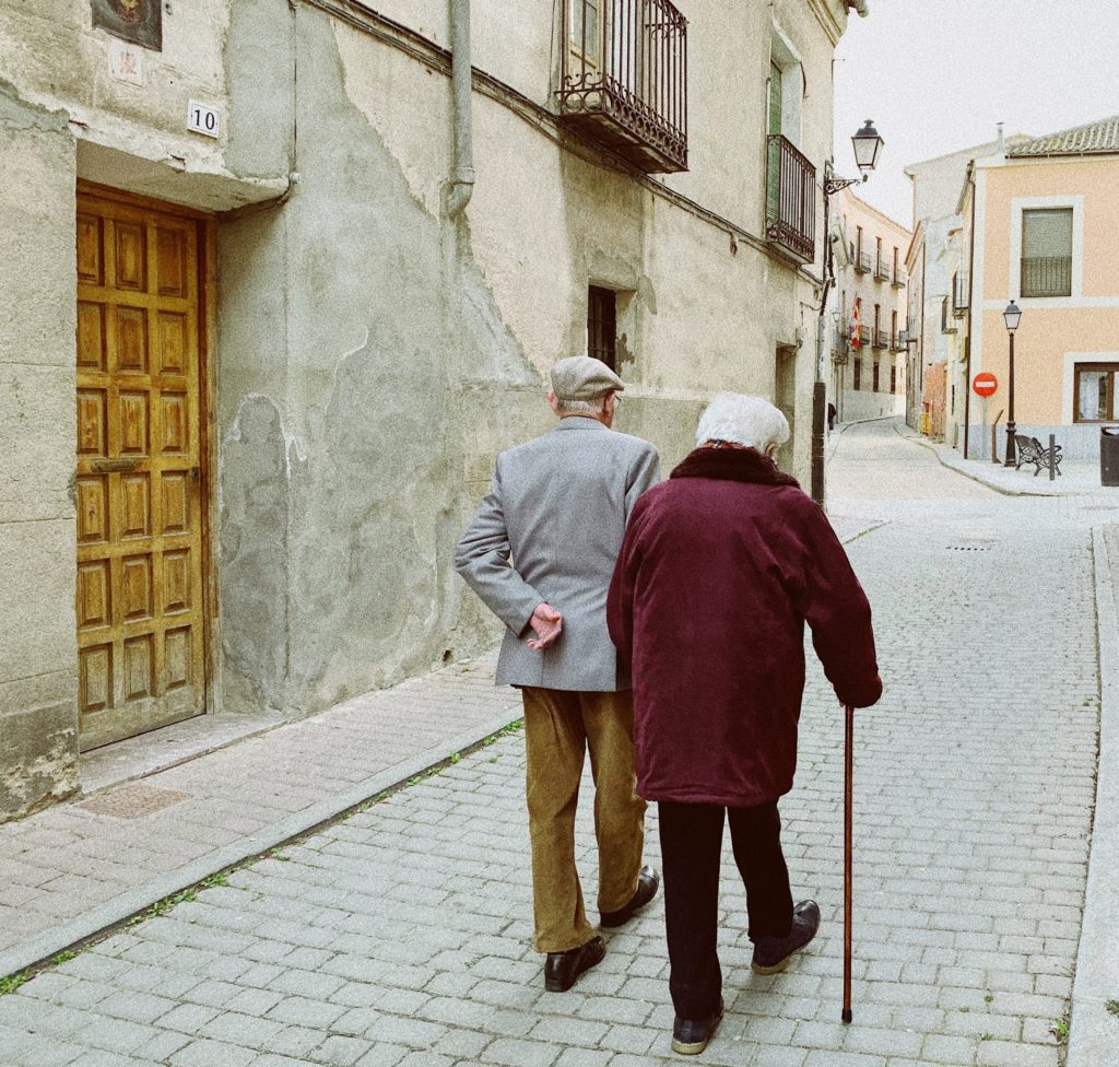 an old man and woman walking down a street