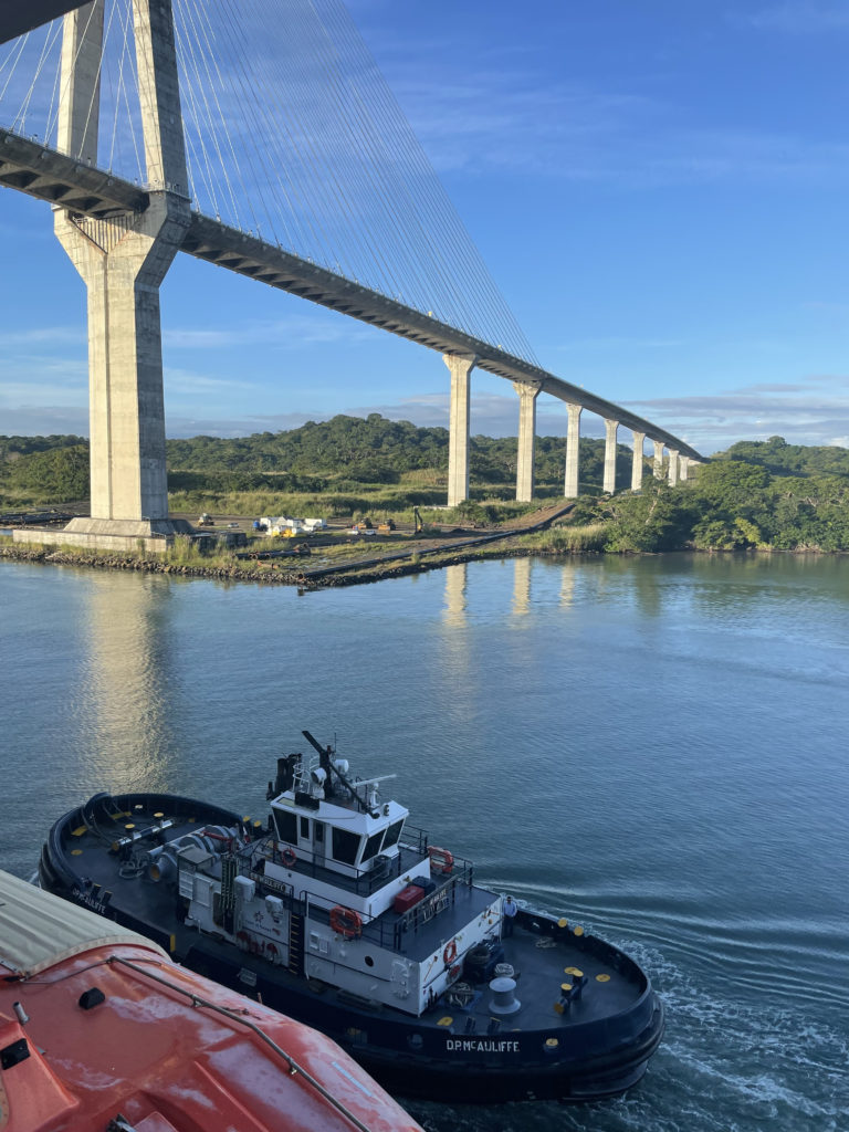 a boat on a body of water with a bridge in the background