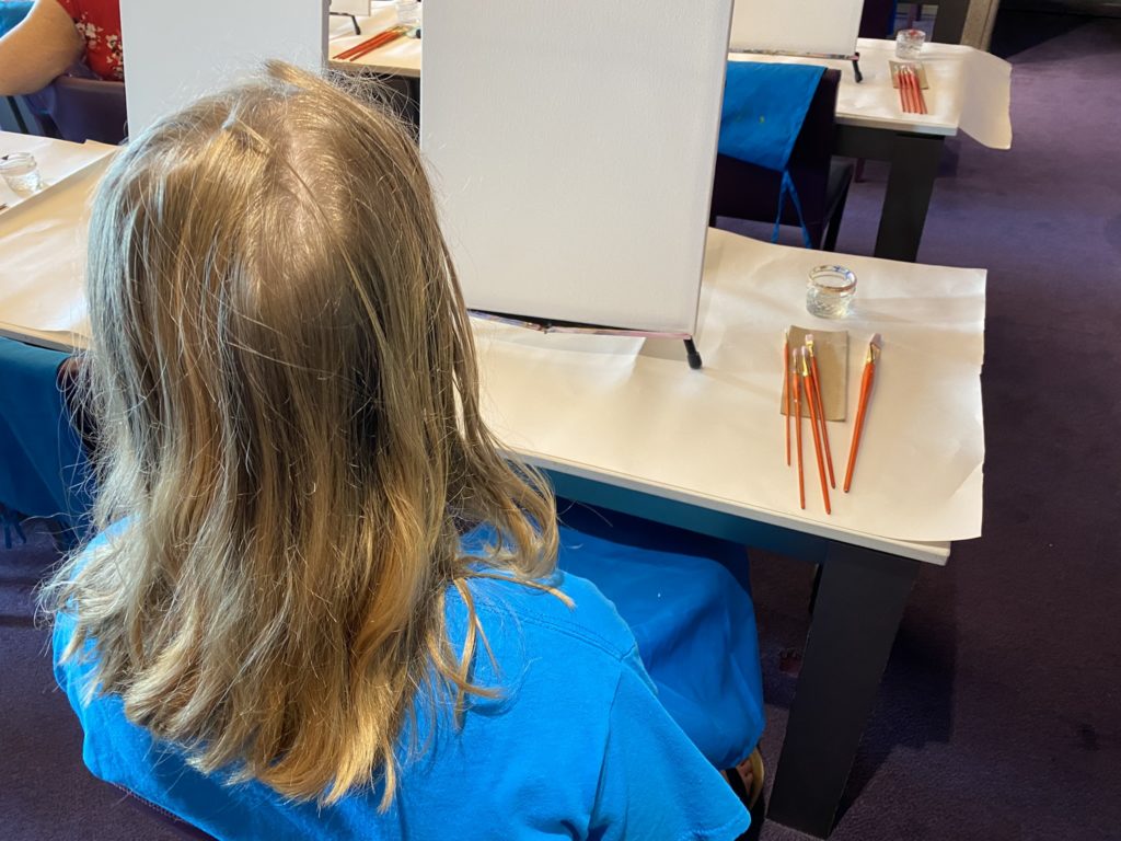 a girl sitting at a desk with pencils on it