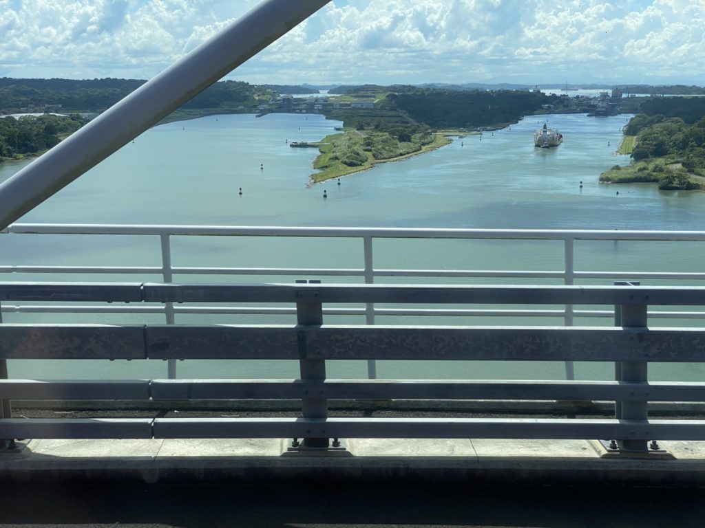 a bridge over water with boats and land in the background