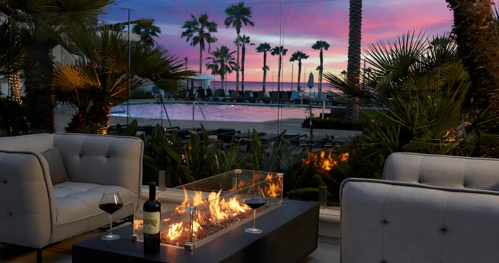 a fire pit with a glass of wine and a pool in the background