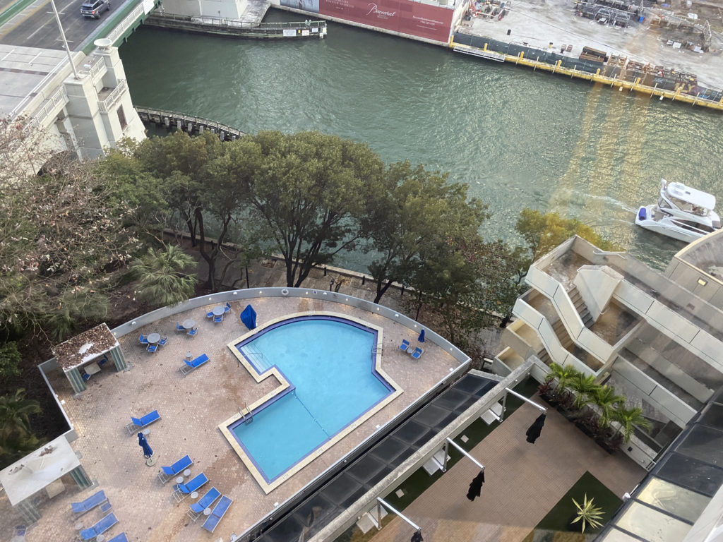 a pool with chairs and trees next to a river