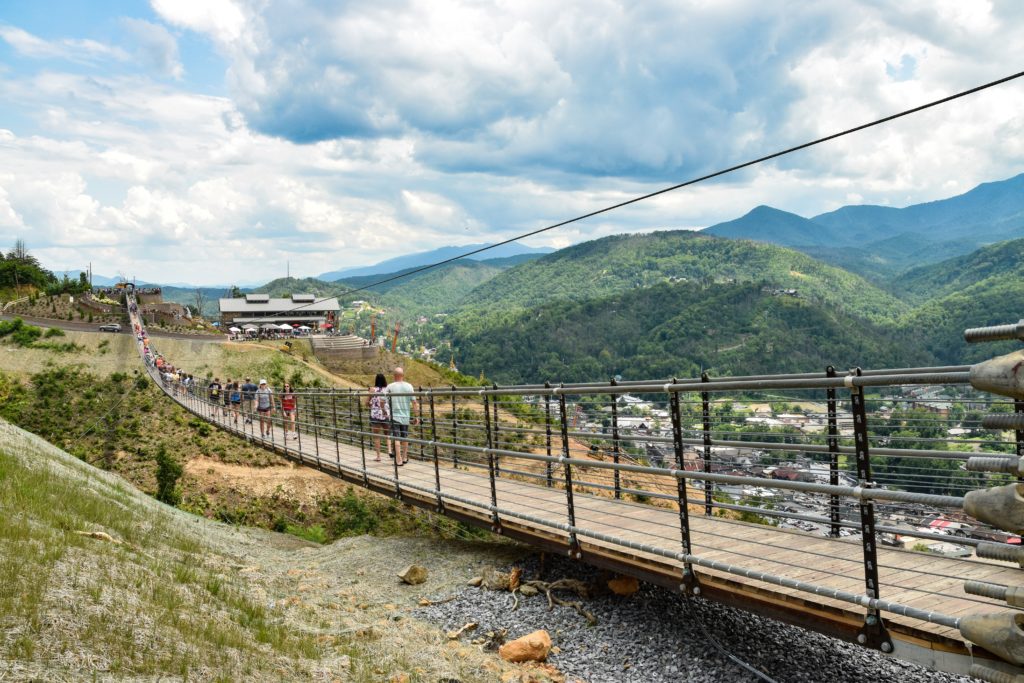 a group of people walking on a bridge over a valley