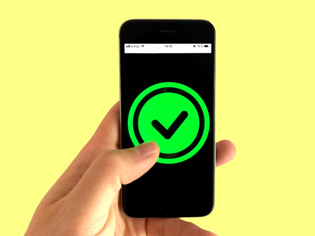 a hand holding a cell phone with a green check mark