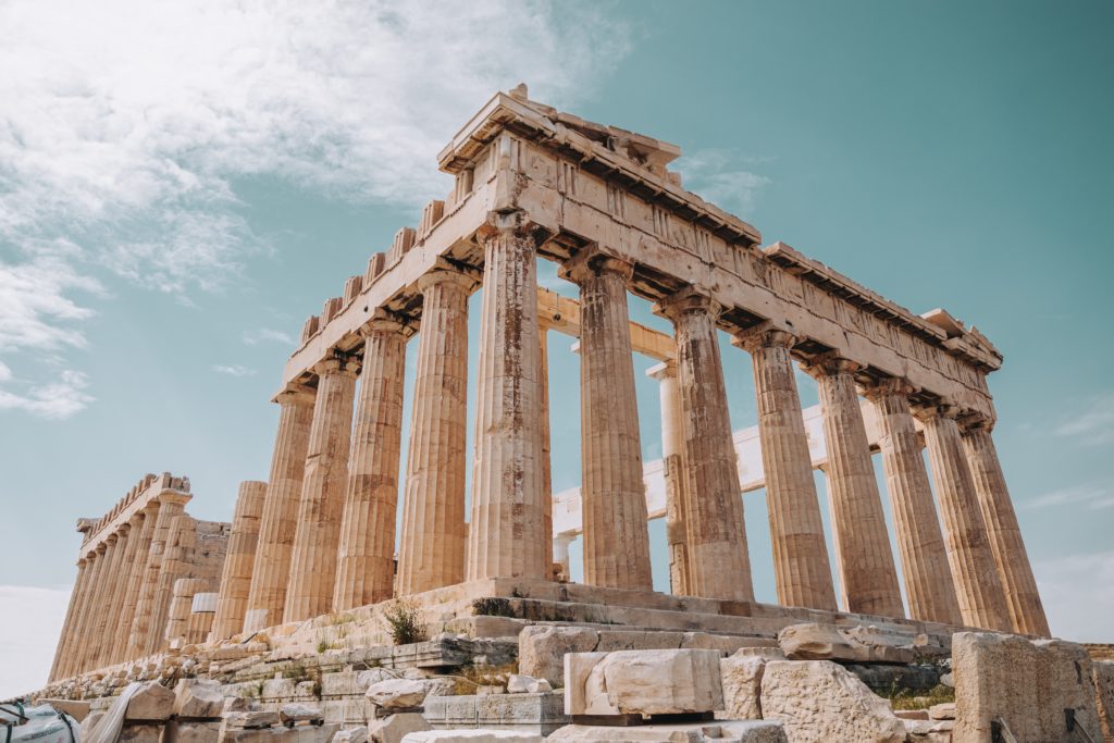 a stone structure with columns with Parthenon in the background