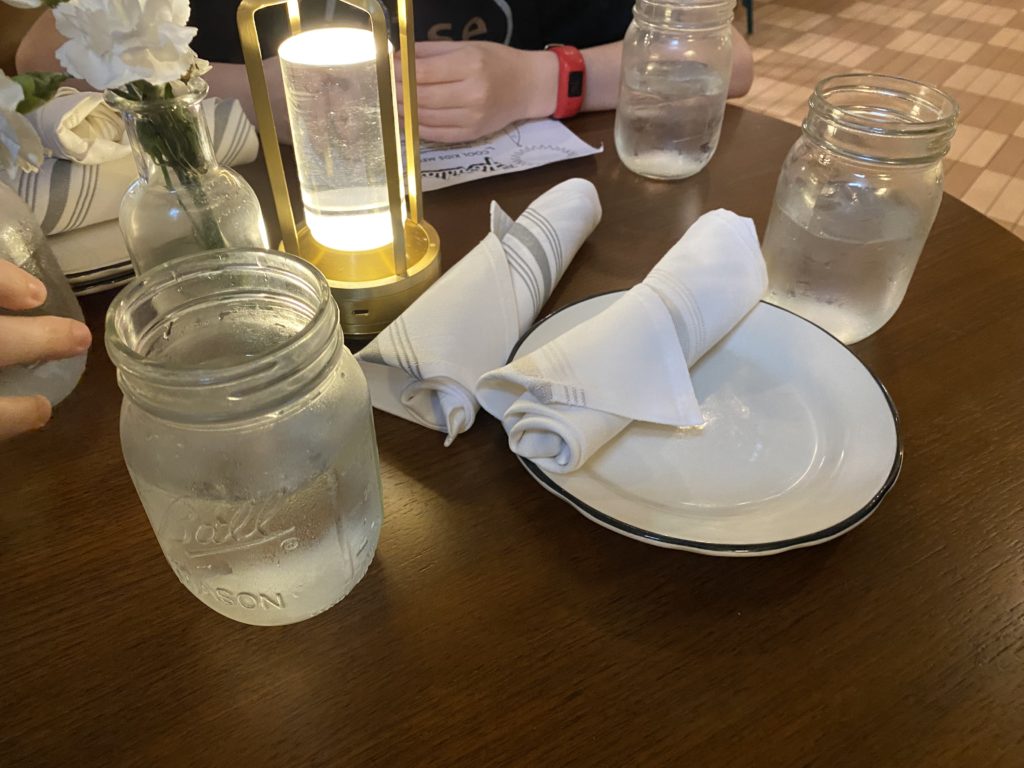a table with a plate napkin and glass jars