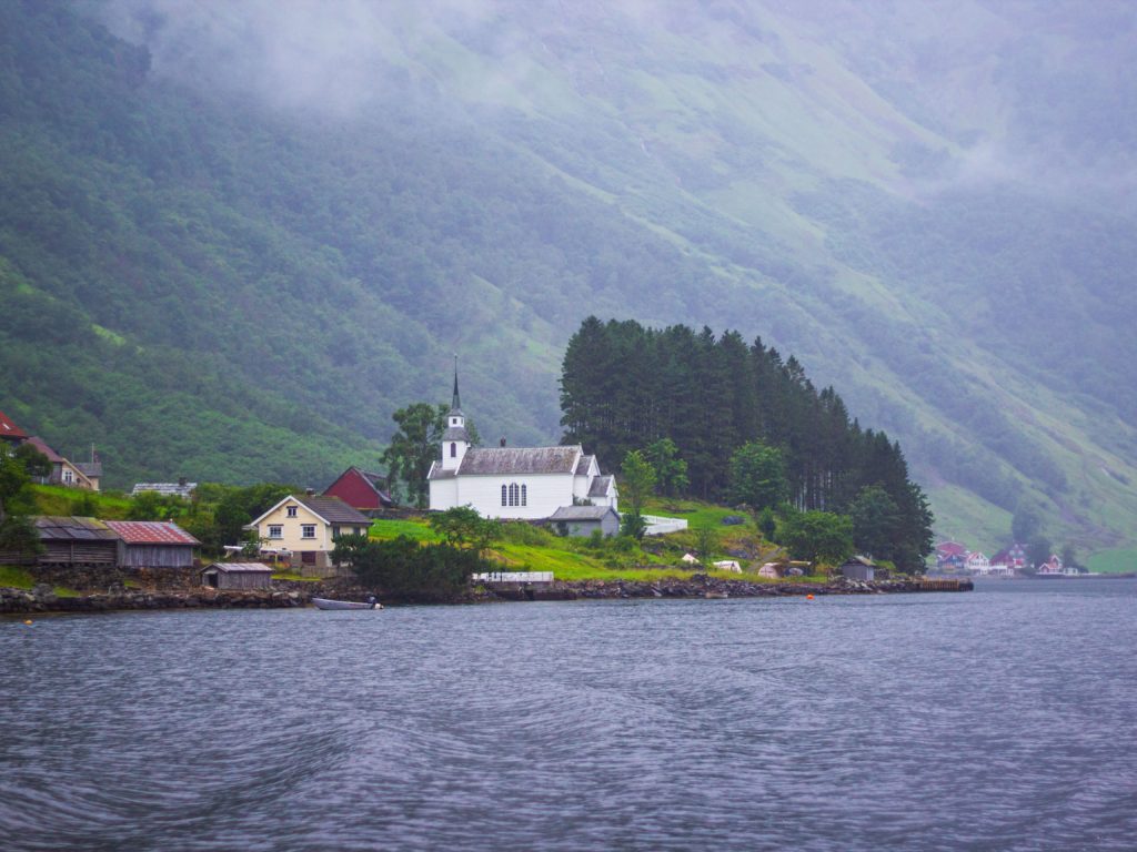 a white building on a hill next to a body of water