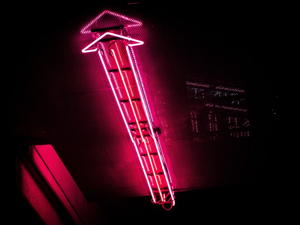 a pink neon arrow sign