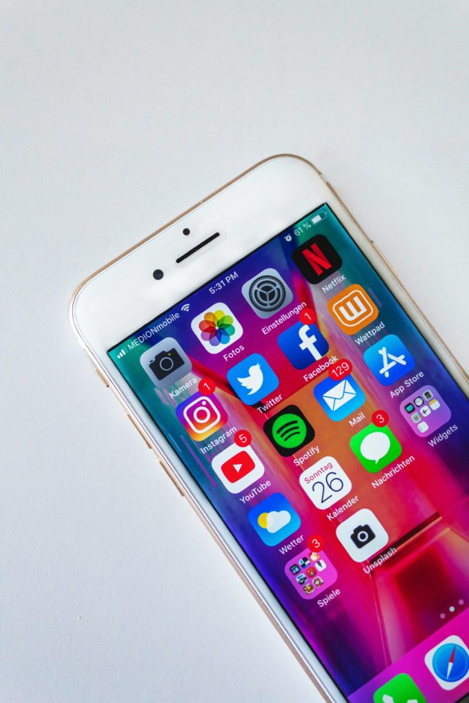 a white cell phone with colorful apps on the screen