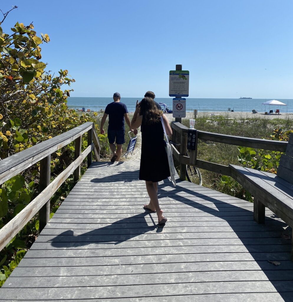 a woman walking on a boardwalk with a man and a bicycle