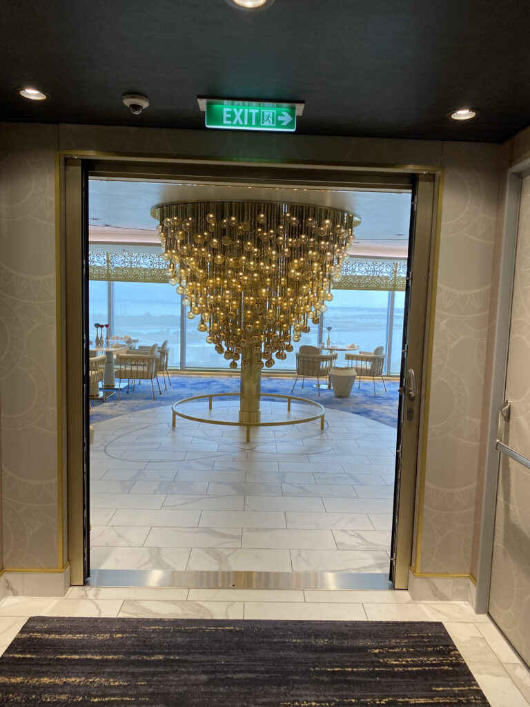 a large chandelier in a room with a green exit sign