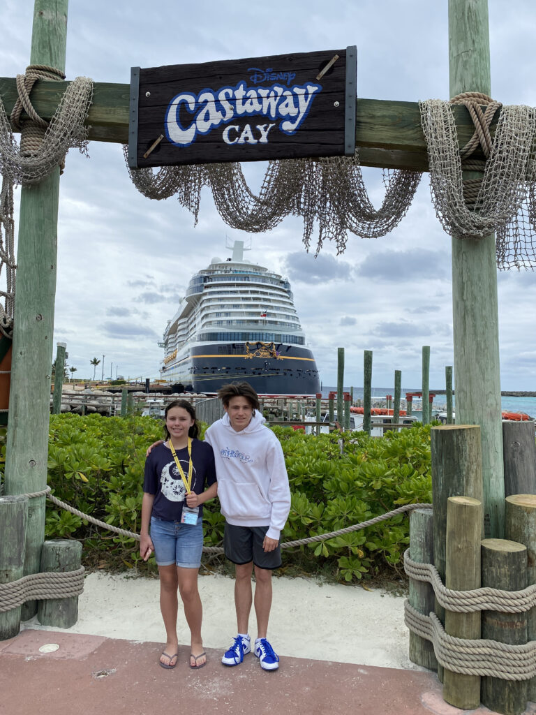 a couple of kids standing in front of a large ship
