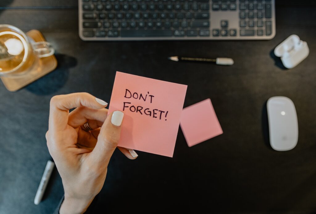 a hand holding a pink note with black text