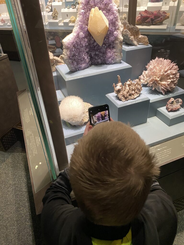 a boy taking a picture of a group of rocks