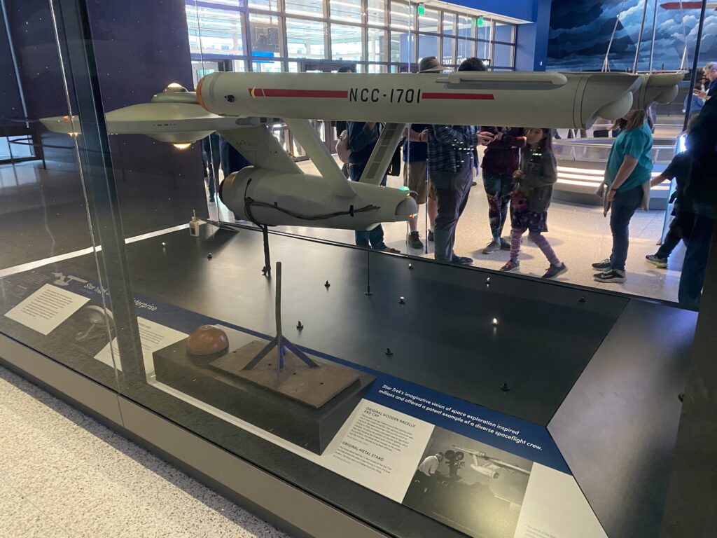 a group of people standing in a room with a display case