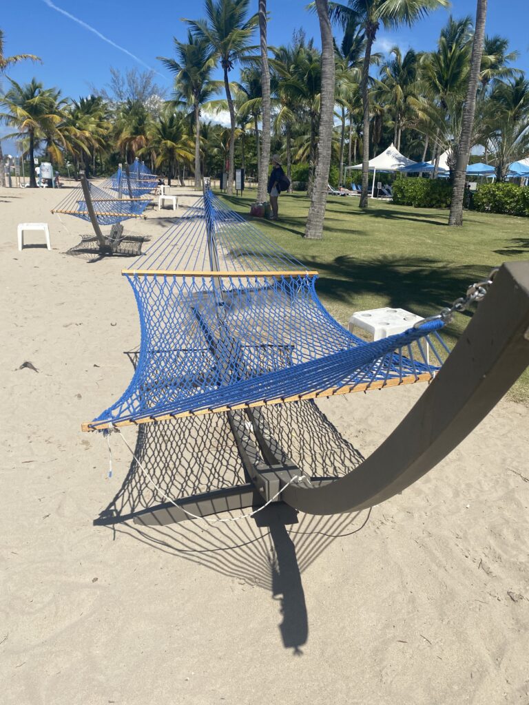 hammocks on a beach with palm trees and people walking on the beach
