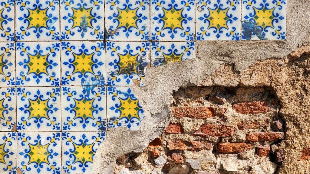 a wall with a broken brick and blue and yellow tile