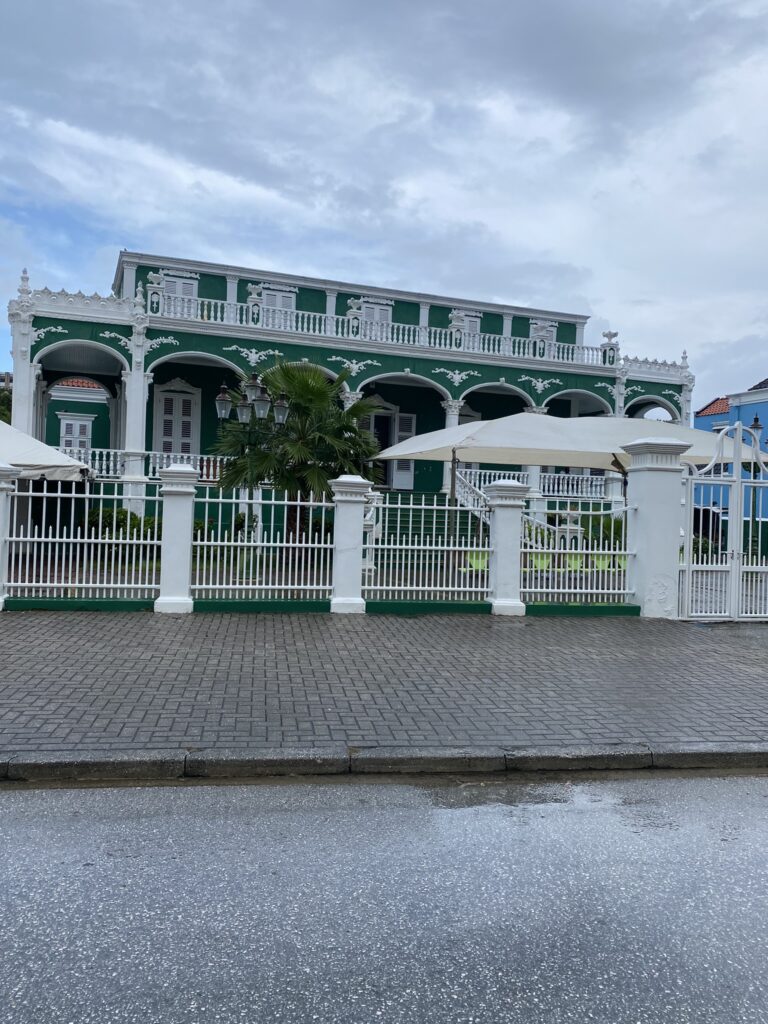 a green house with white fence and umbrellas