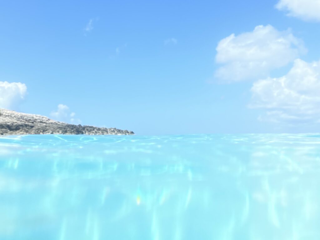 a clear blue water with a hill in the background