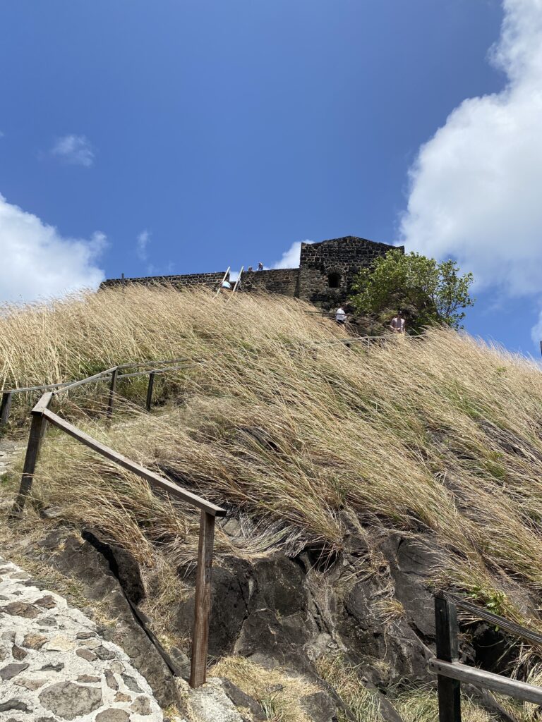 a stone building on a hill with a wooden railing