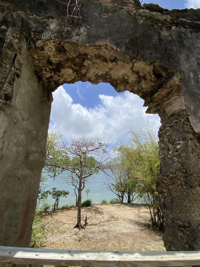 a stone arch with trees and water in the background