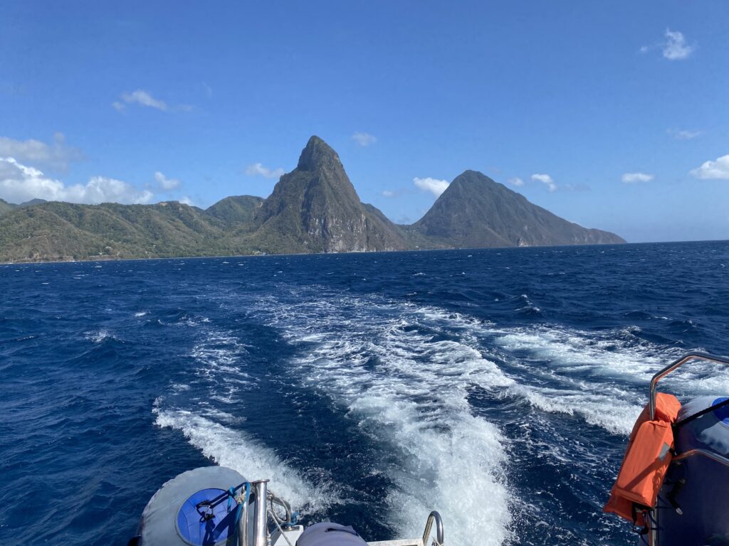 a boat on the water with mountains in the background with Pitons in the background