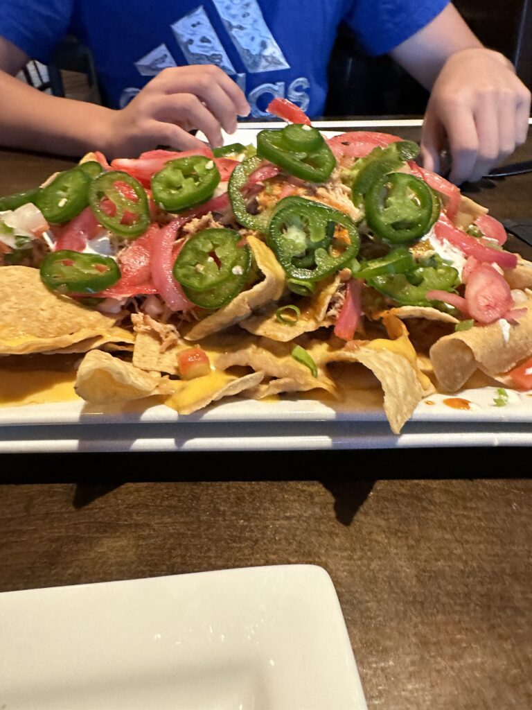 a plate of nachos with jalapenos and tomatoes