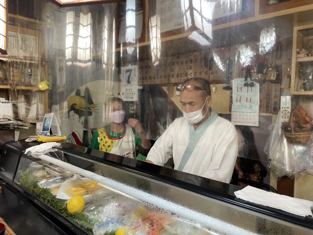 a man wearing a face mask behind a counter with food