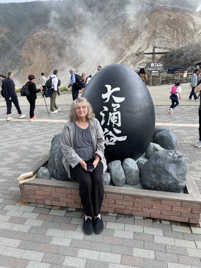 a woman sitting on a rock with a large black object with white writing