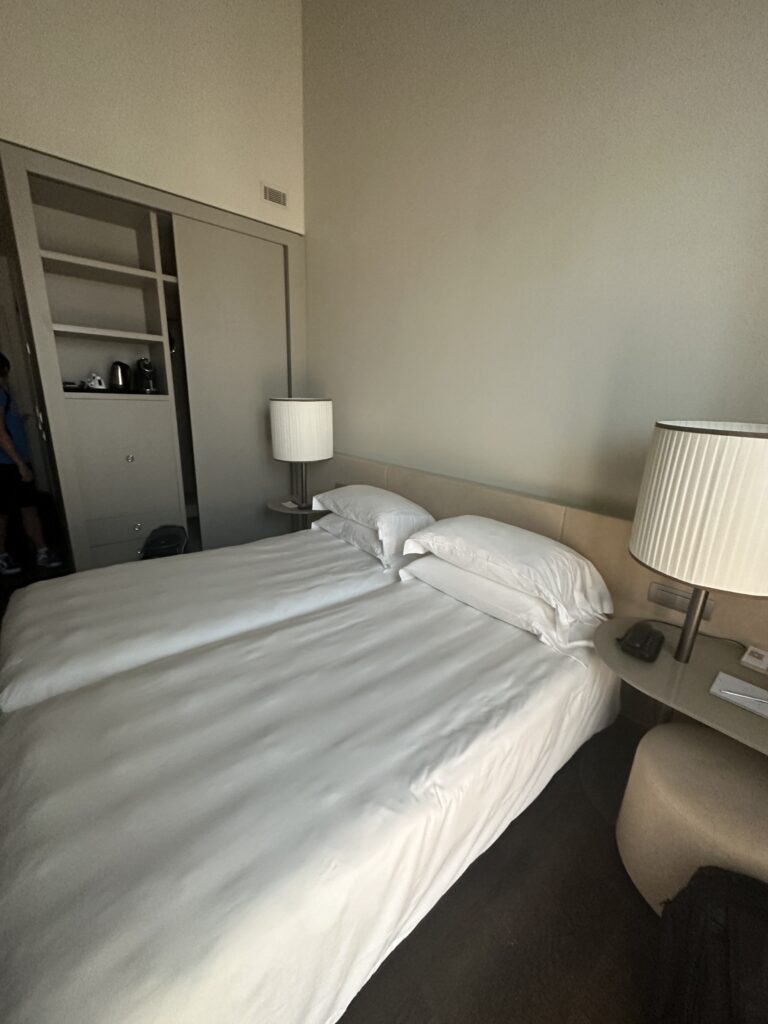a bed with white sheets and lamps in a room