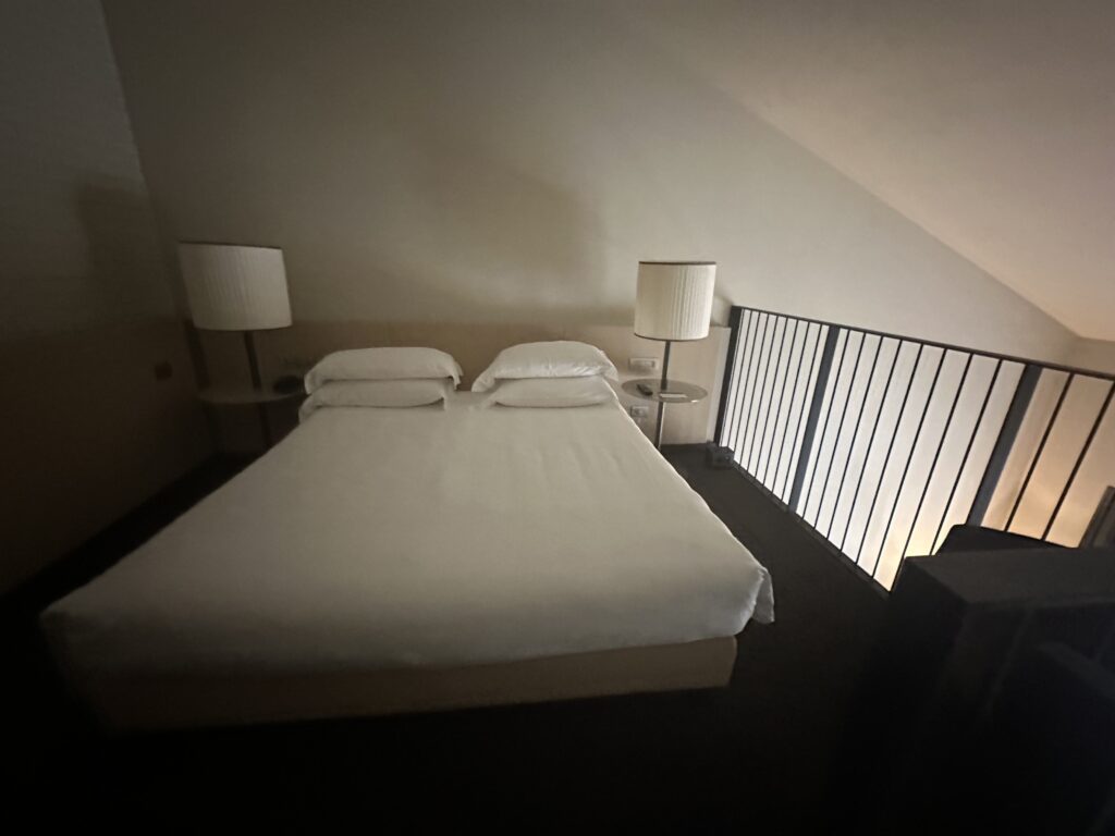 a bed with white sheets and lamps