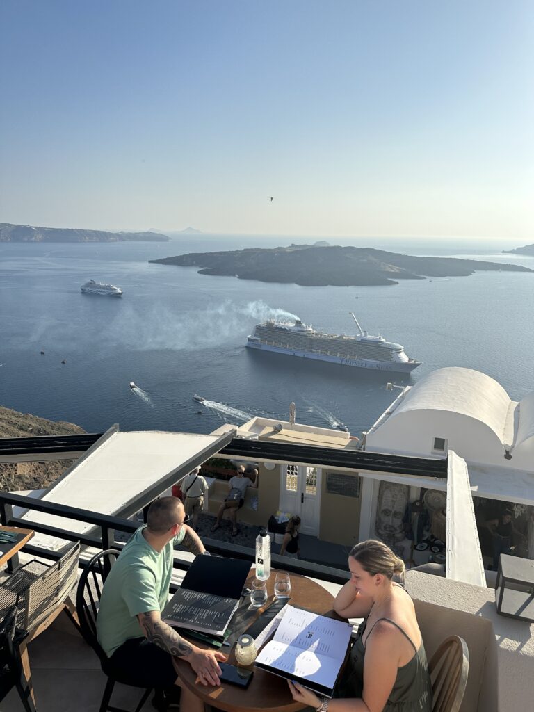 a group of people sitting at a table with a cruise ship in the background