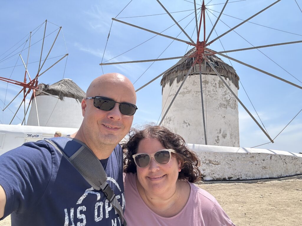 a man and woman taking a selfie in front of windmills