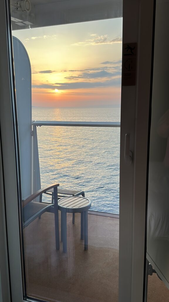 a balcony with a chair and a railing overlooking the ocean