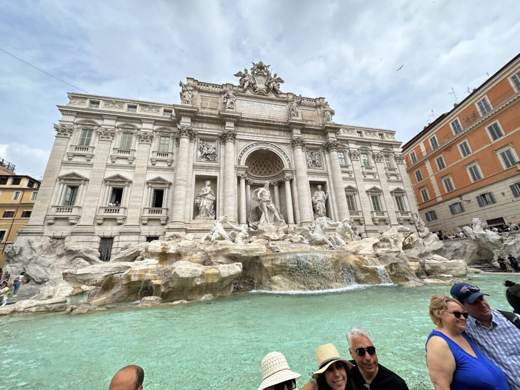 a group of people standing in front of a fountain with Trevi Fountain in the background
