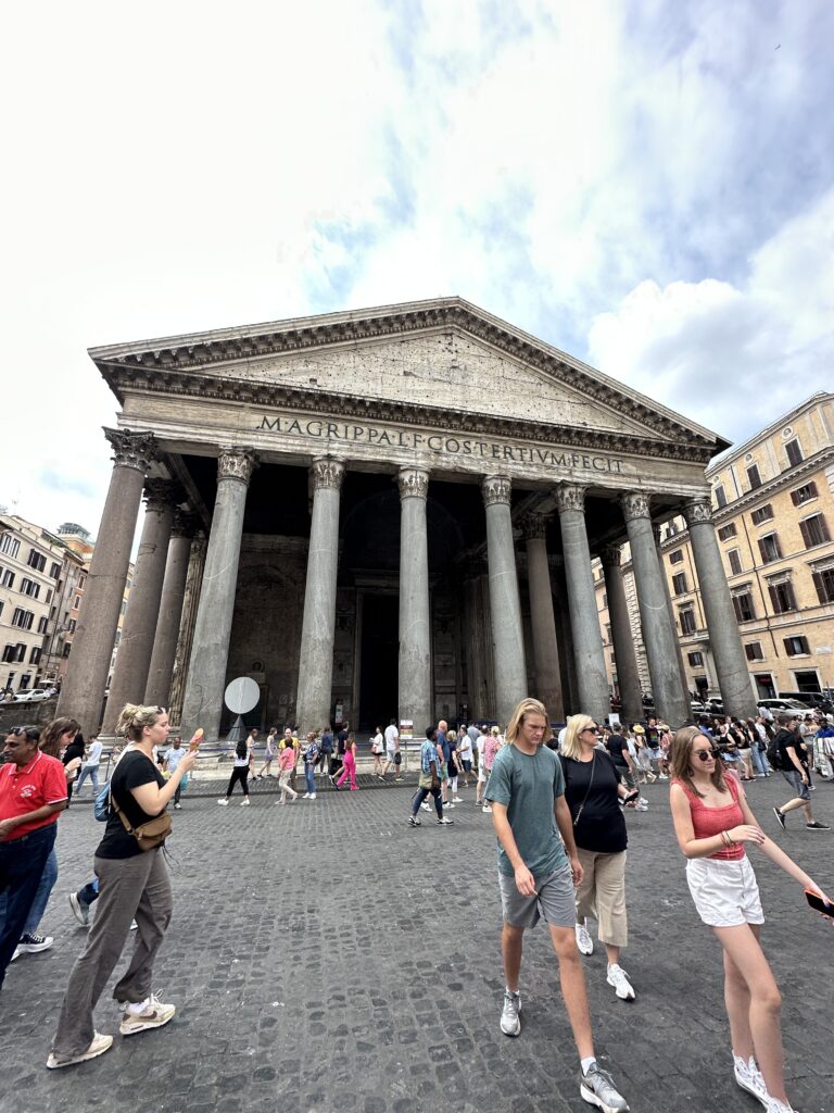 a group of people walking in front of a building with columns