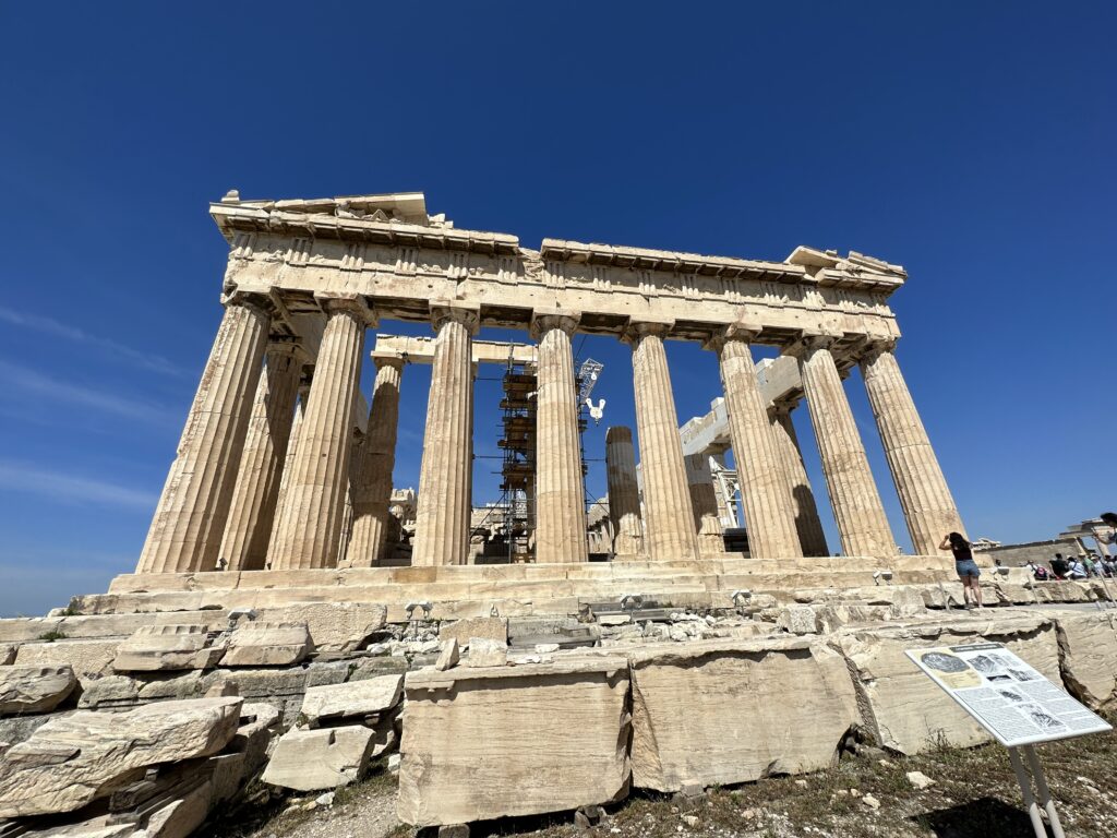 a person standing next to Parthenon