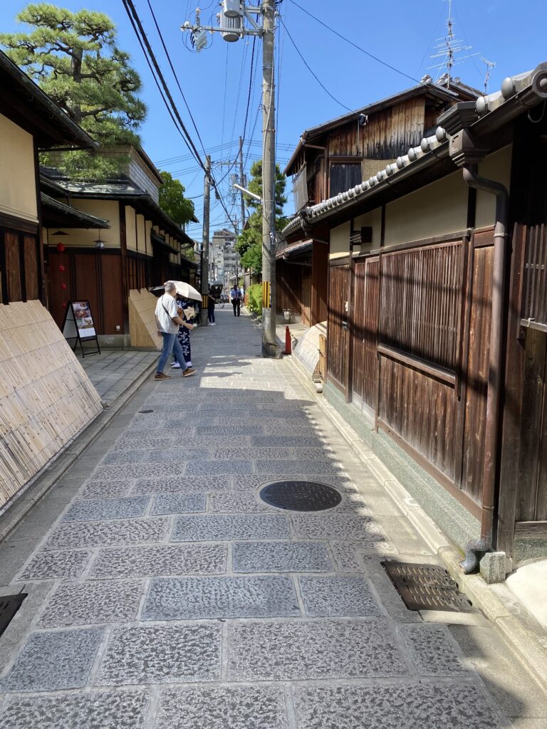 a person walking down a sidewalk with a person holding an umbrella