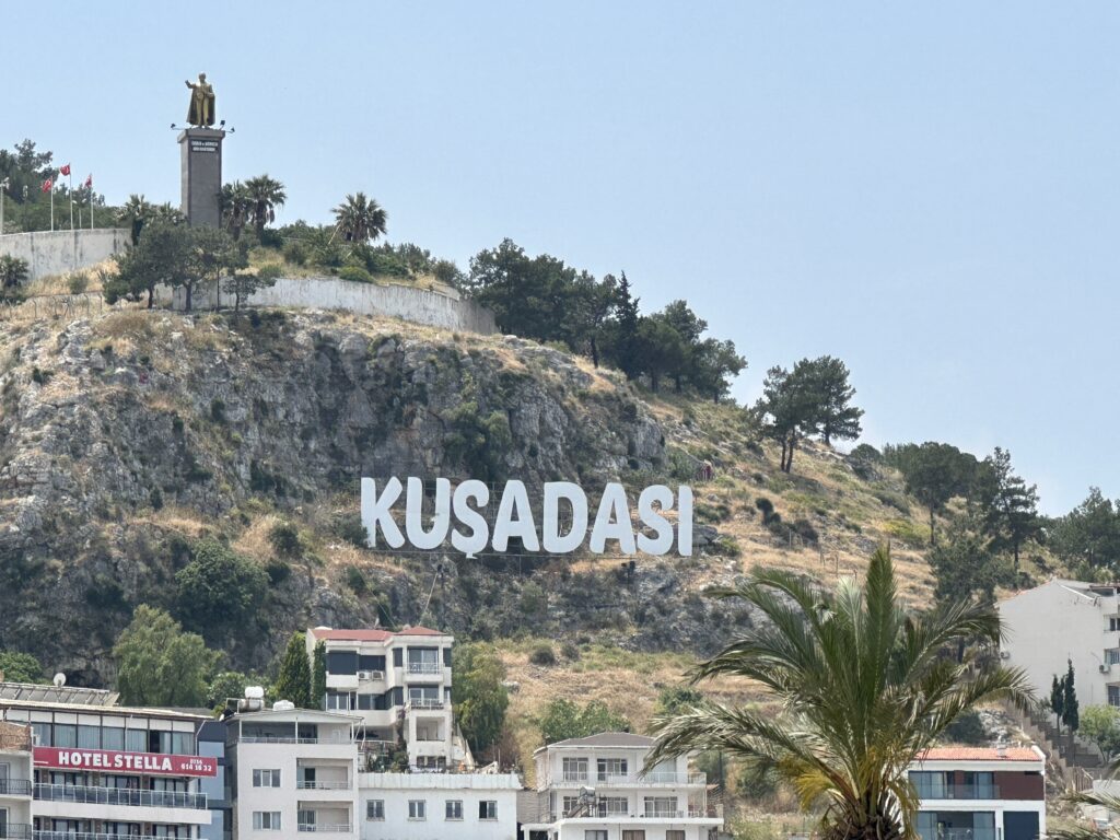 a large sign on a hill with buildings and trees with Hollywood Sign in the background