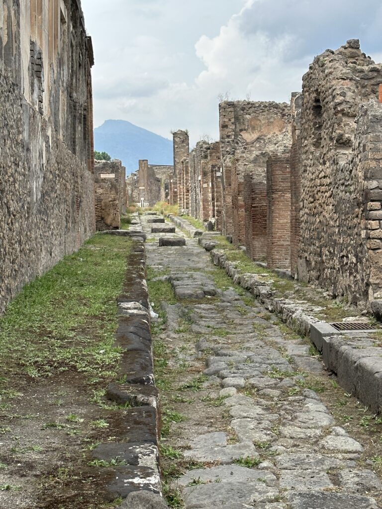 a stone alley way with Pompeii in the background