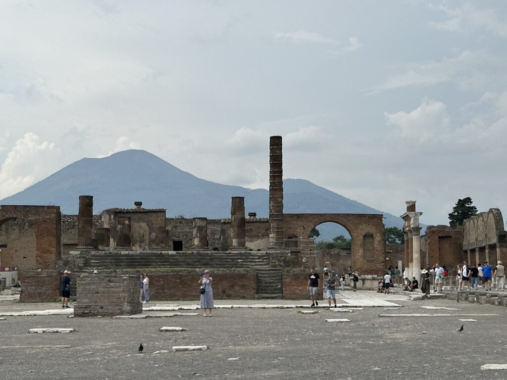 a group of people standing in front of a ruined building with Temple of Jupiter in the background