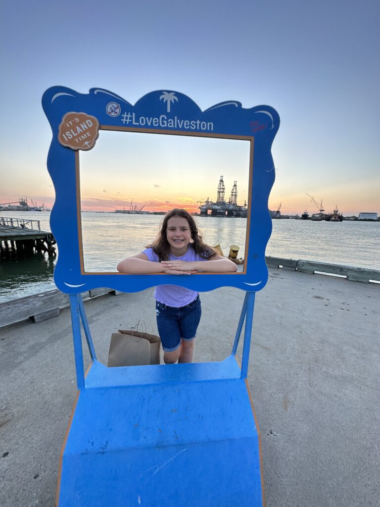 a girl standing in a frame with a picture of a beach and water